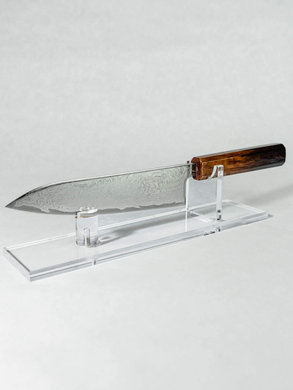 OUL 10A Uzu Japanese chef knife's full profile displayed on a clear acrylic stand.