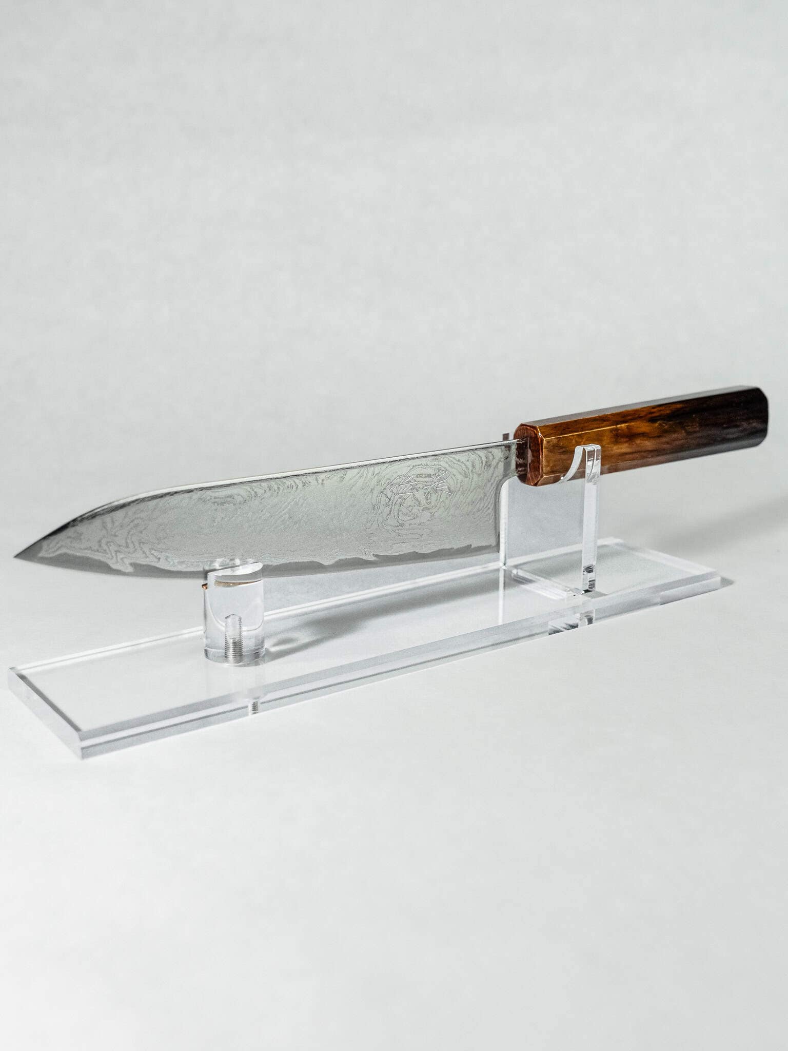 OUL 10A Uzu Japanese chef knife's full profile displayed on a clear acrylic stand.
