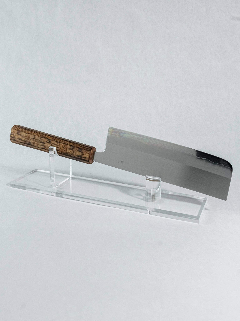 Nakiri knife with wooden handle on a clear stand against a light gray background