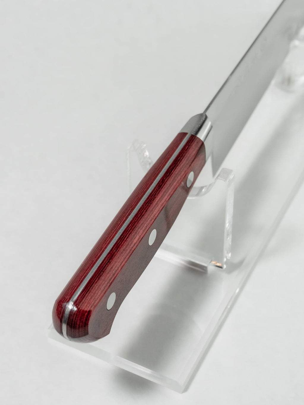 Top view of the red pakkawood handle with bolster detail on a white background.