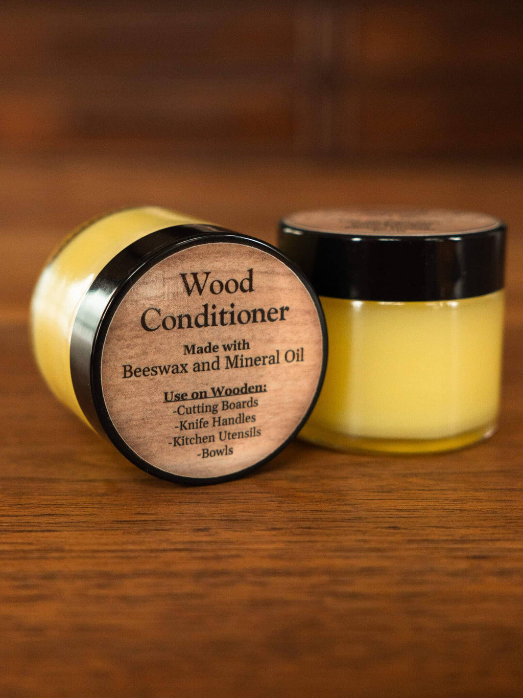 Two jars of wood conditioner with wooden labels on a wooden surface.