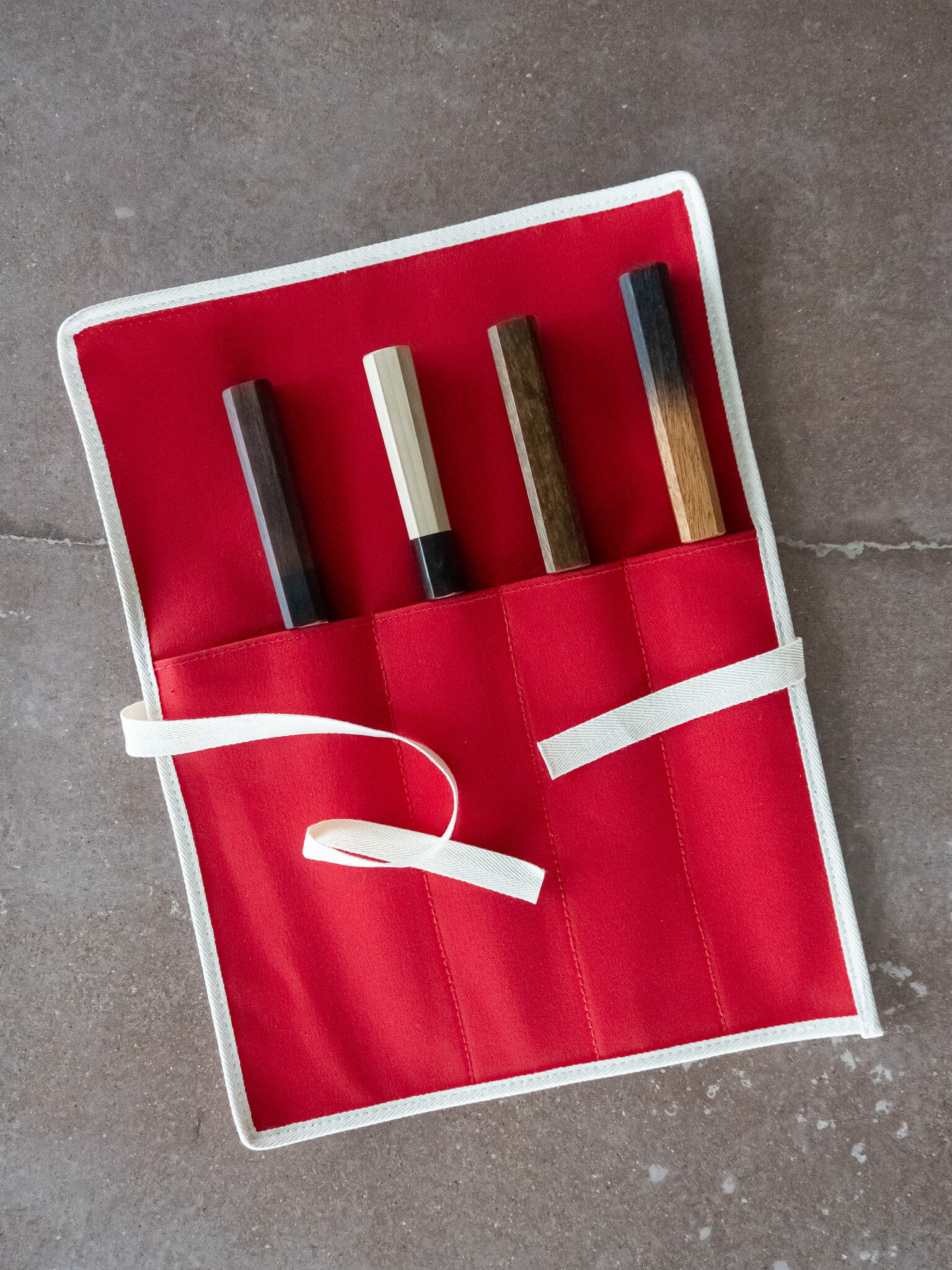 Detail of the canvas tie used to secure the knife roll unfurled. All four knives are tucked securely in the slots.