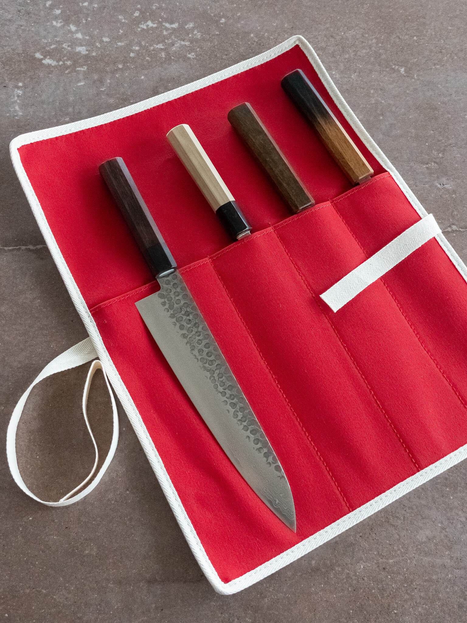 Compact red canvas knife roll designed for chefs and home cooks on the go.