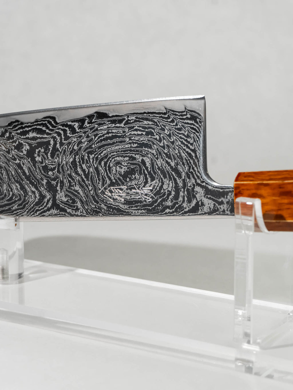 Close-up of the OUL Uzu Nakiri knife blade showing twisted Damascus pattern and sharp AUS-10A core.