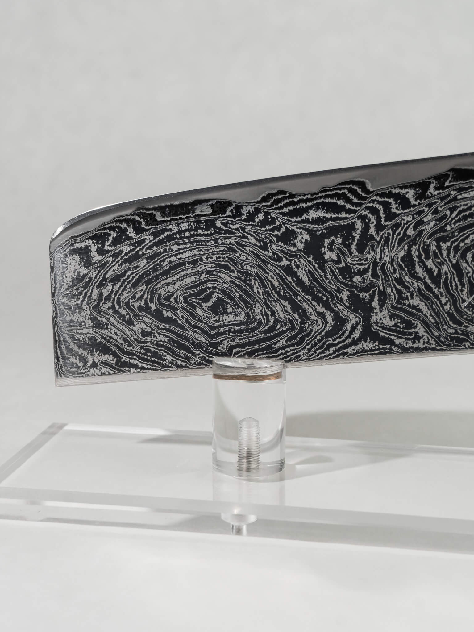 Close-up of the OUL Uzu Nakiri blade showing twisted Damascus pattern and sharp AUS-10A core.