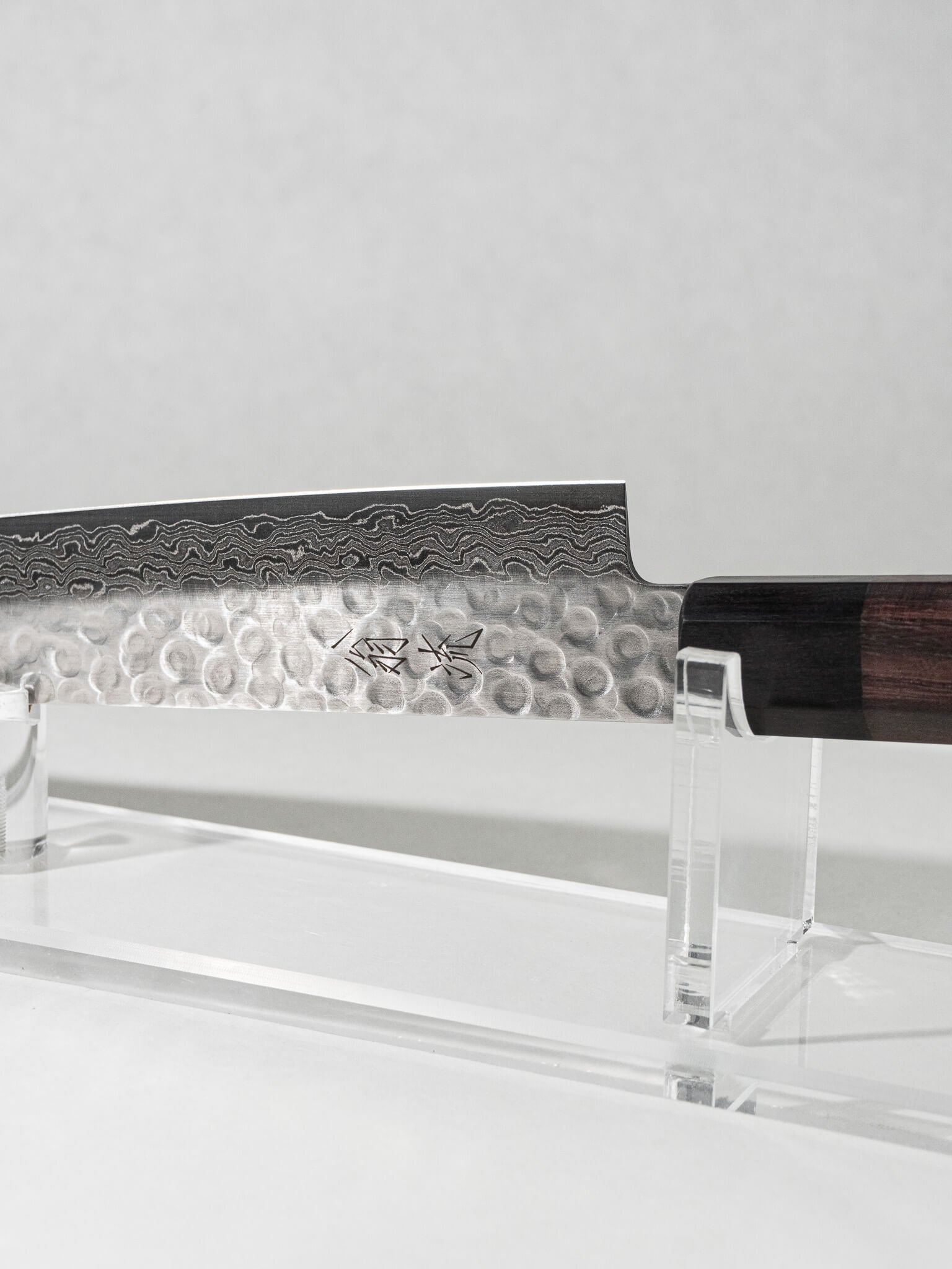 Close-up of the OUL Damascus Tsuchime Sujihiki knife, highlighting the hammered tsuchime finish, intricate Damascus layering, and balanced handle for precise slicing and control.