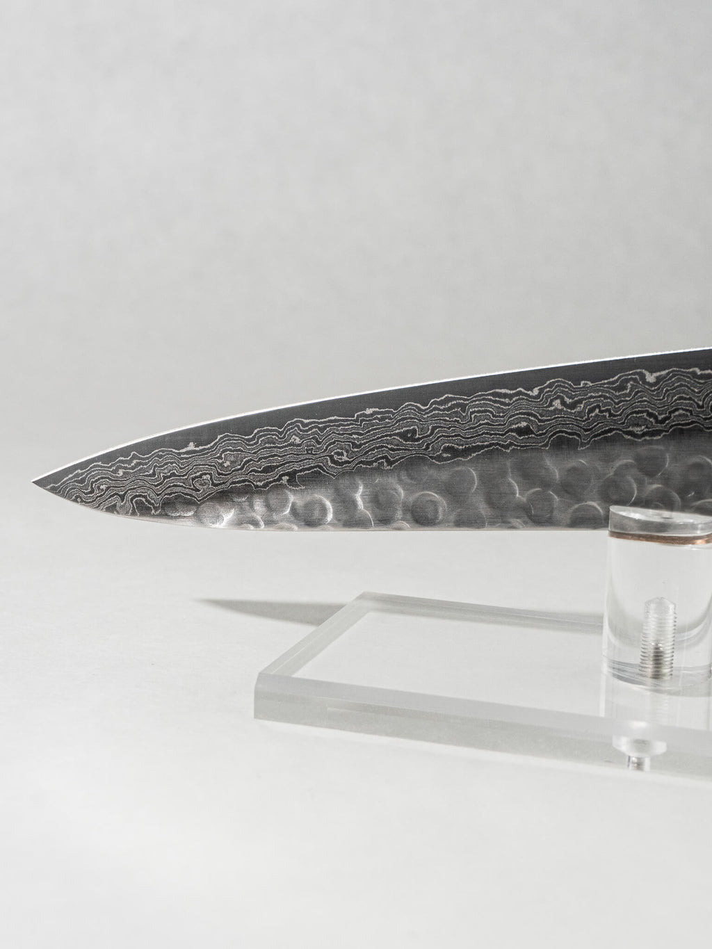 Close-up of the OUL Damascus Tsuchime slicer tip, showcasing the sharp point, detailed Damascus patterning, and hammered tsuchime finish for precise, effortless slicing.