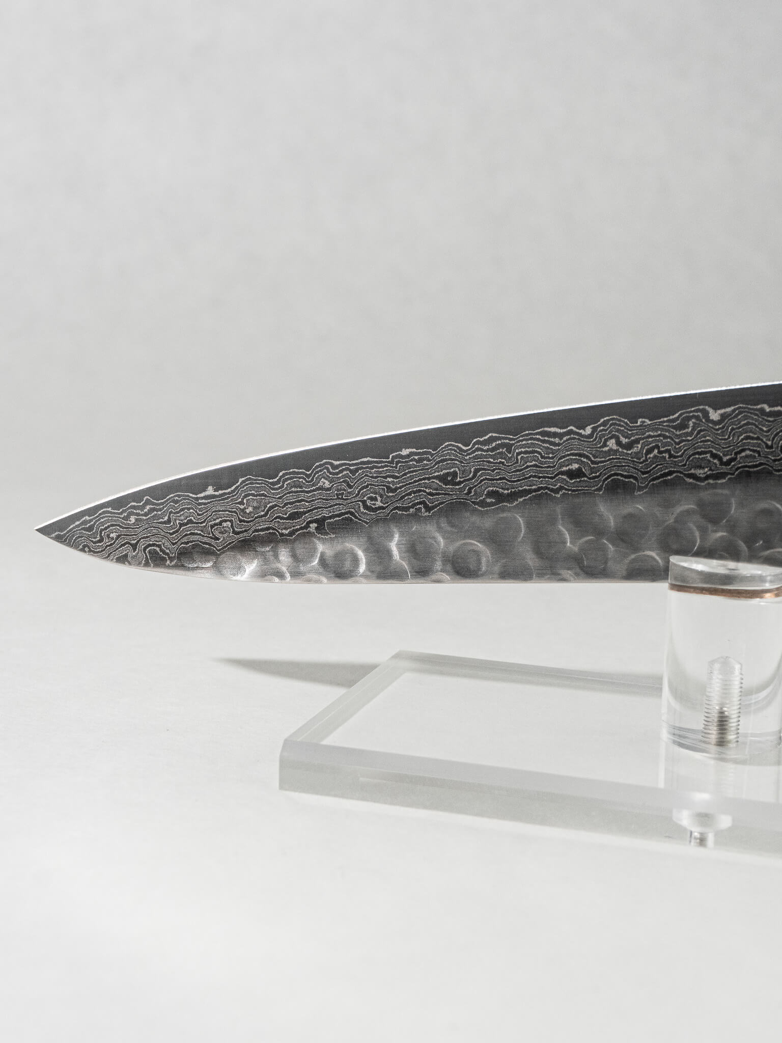 Close-up of the OUL Damascus Tsuchime slicer tip, showcasing the sharp point, detailed Damascus patterning, and hammered tsuchime finish for precise, effortless slicing.