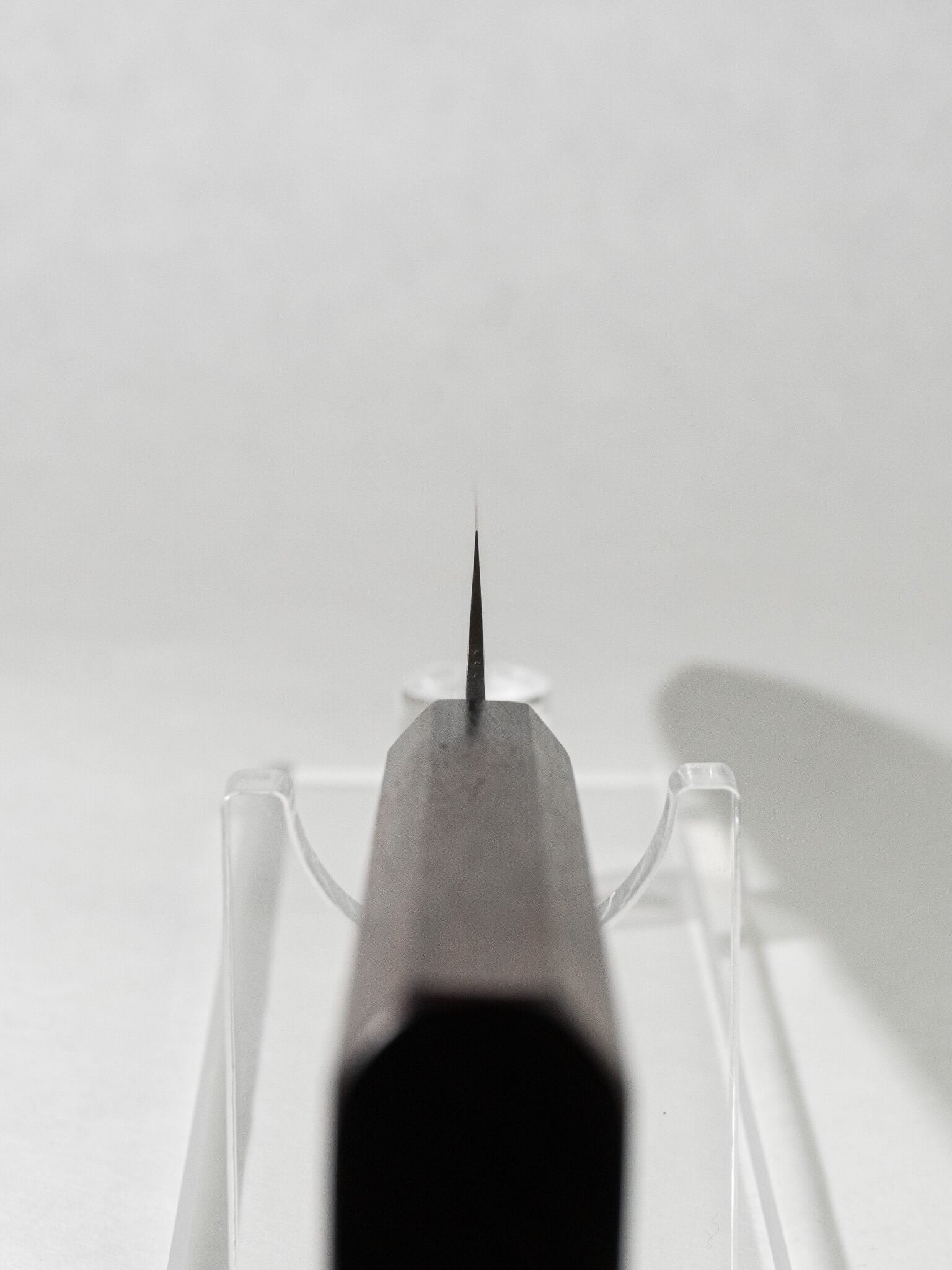 Close-up of the OUL Damascus Tsuchime Sujihiki knife choil, showcasing the precise craftsmanship and functional design for safe and controlled cutting.