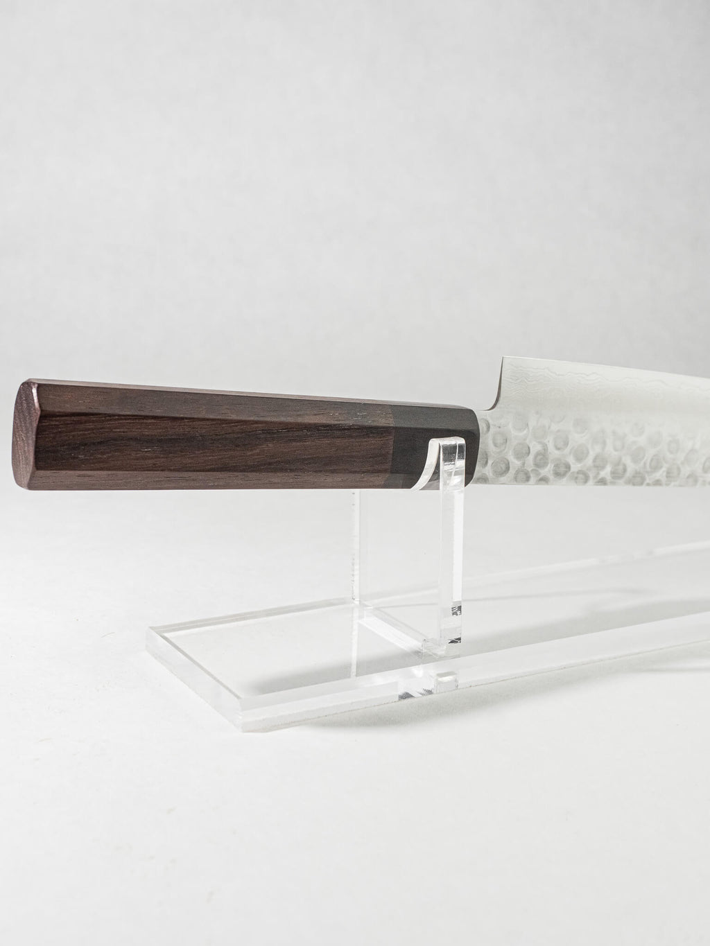 Close-up of the OUL Damascus Tsuchime Sujihiki knife handle, highlighting its ergonomic design, smooth finish, and comfortable grip for optimal control and balance. Octagonal rosewood handle with black Pakkawood ferrule.