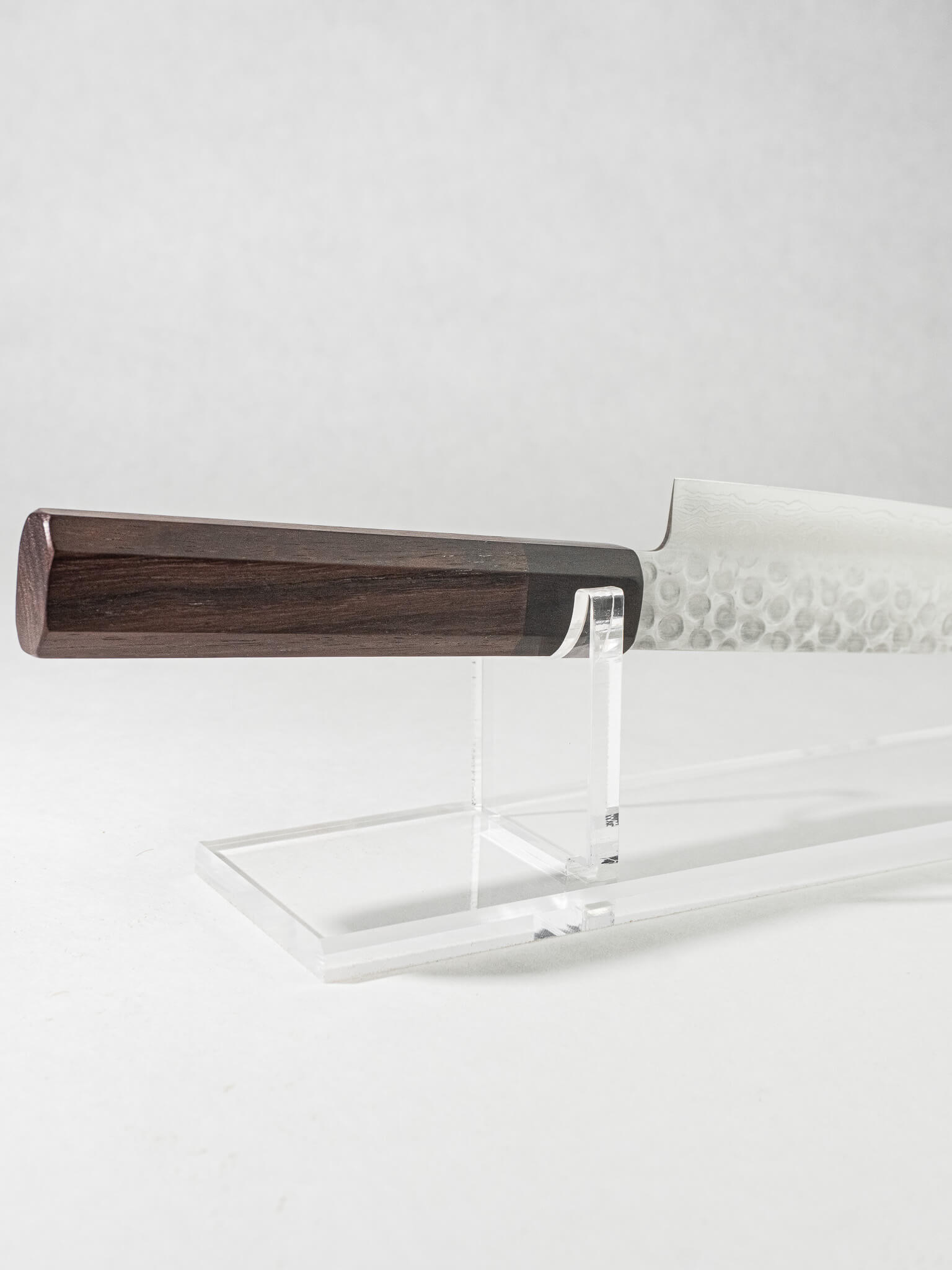 Close-up of the OUL Damascus Tsuchime Sujihiki knife handle, highlighting its ergonomic design, smooth finish, and comfortable grip for optimal control and balance. Octagonal rosewood handle with black Pakkawood ferrule.