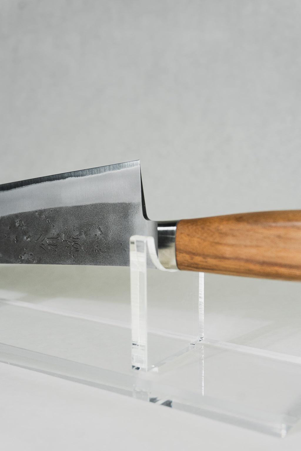 Heel area of gyuto knife ideal for chopping and push cuts. Showing a stainless bolster connecting the western-style walnut handle