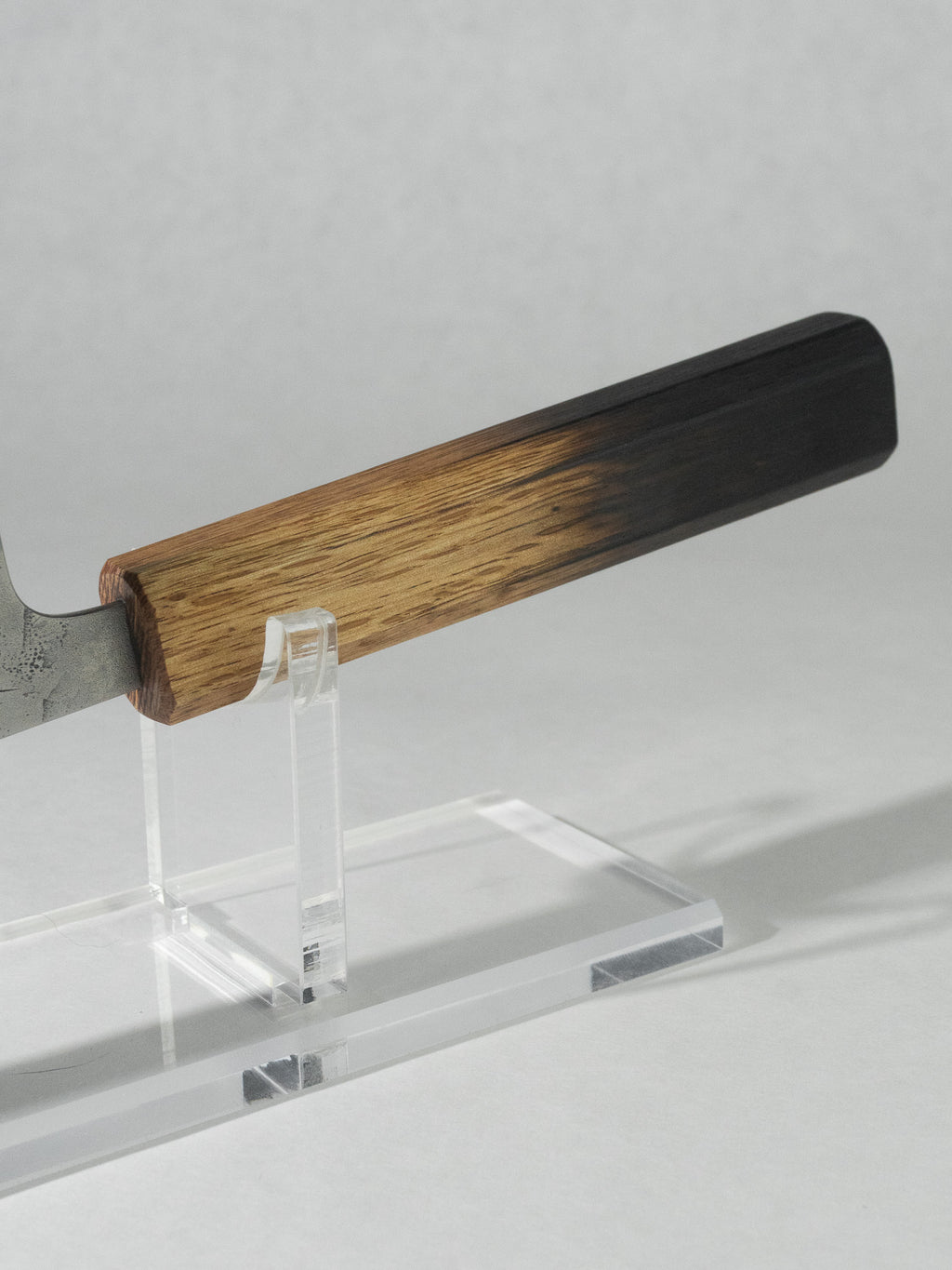 Close-up of the octagonal burnt oak handle on the OUL Nakiri, with it's unique color gradient. The octagonal shape offers a secure and comfortable grip.