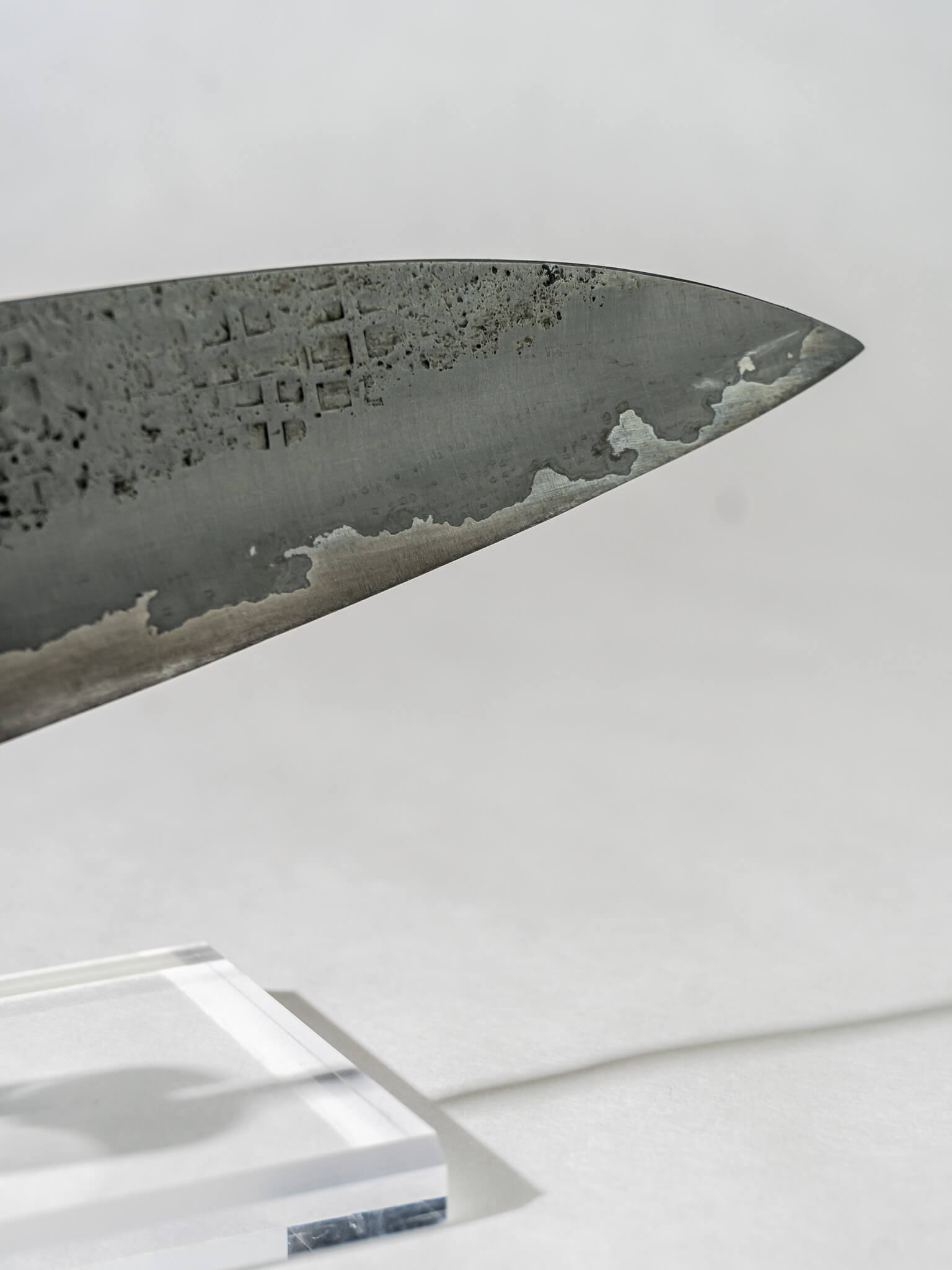 close up of the Pisau Dapur 230mm gyuto knife with a sharp tip and unique square hammering. There is a small trace of patina because of the recycled material that adds depth to the patterning.