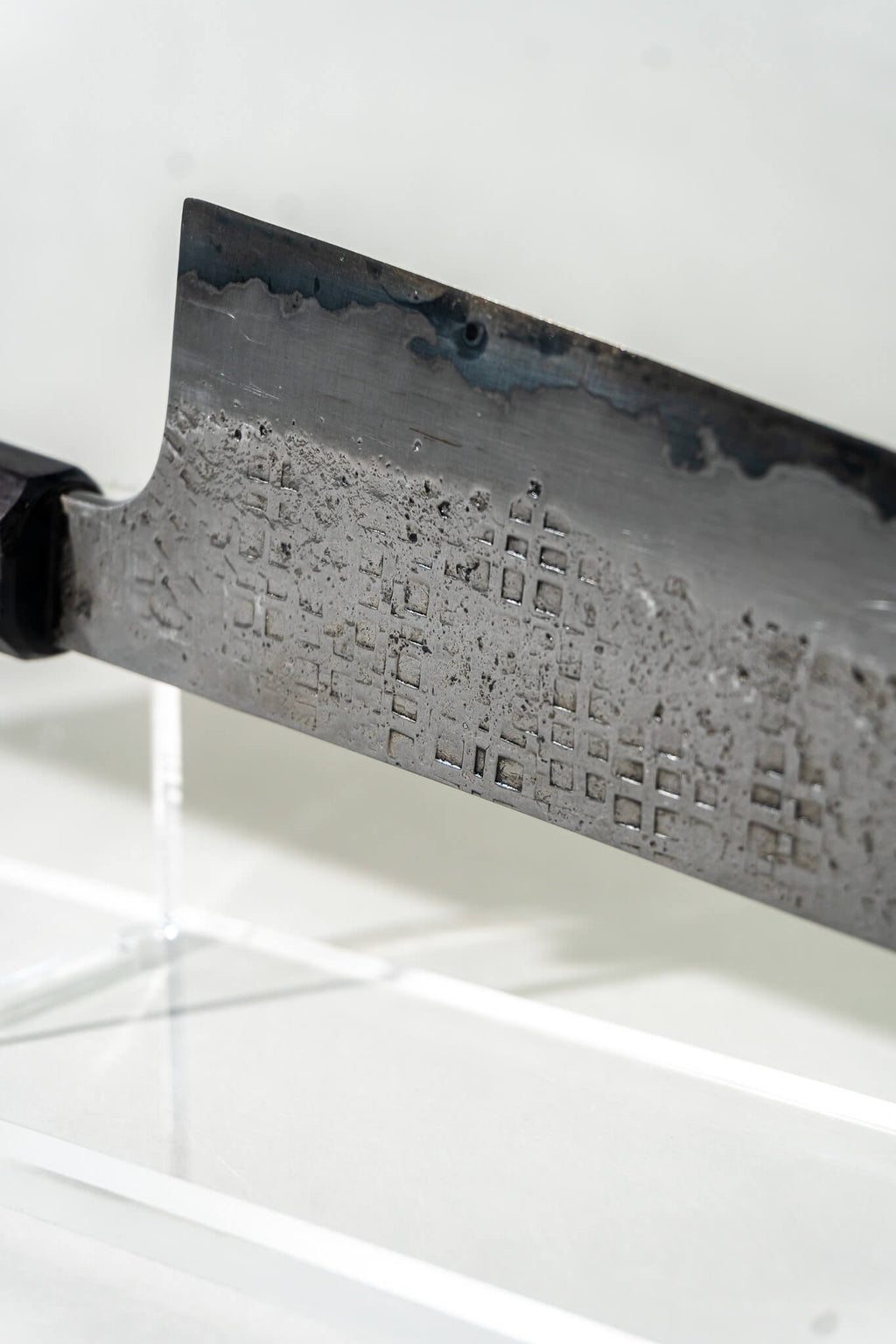 Close-up of the Pisau Dapur 230mm gyuto knife, highlighting the sharp tip and distinctive square hammering. Subtle patina from the recycled steel adds depth and character to the blade’s patterning.