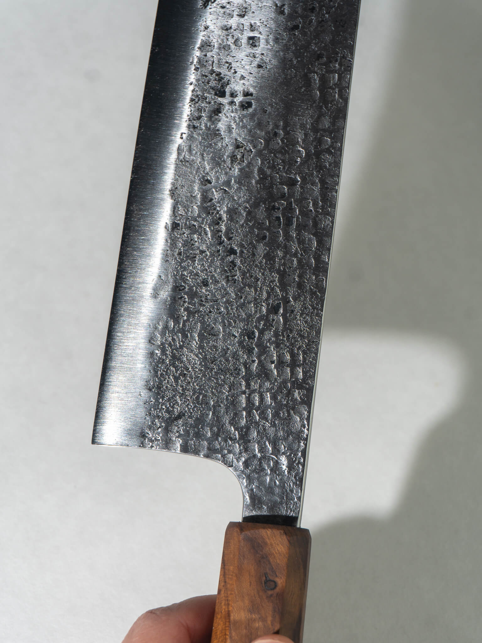 Close-up of hand-hammered tsuchime texture on Pisau Dapur Nakiri knife blade. Hand hammering pattern of small squares. 
