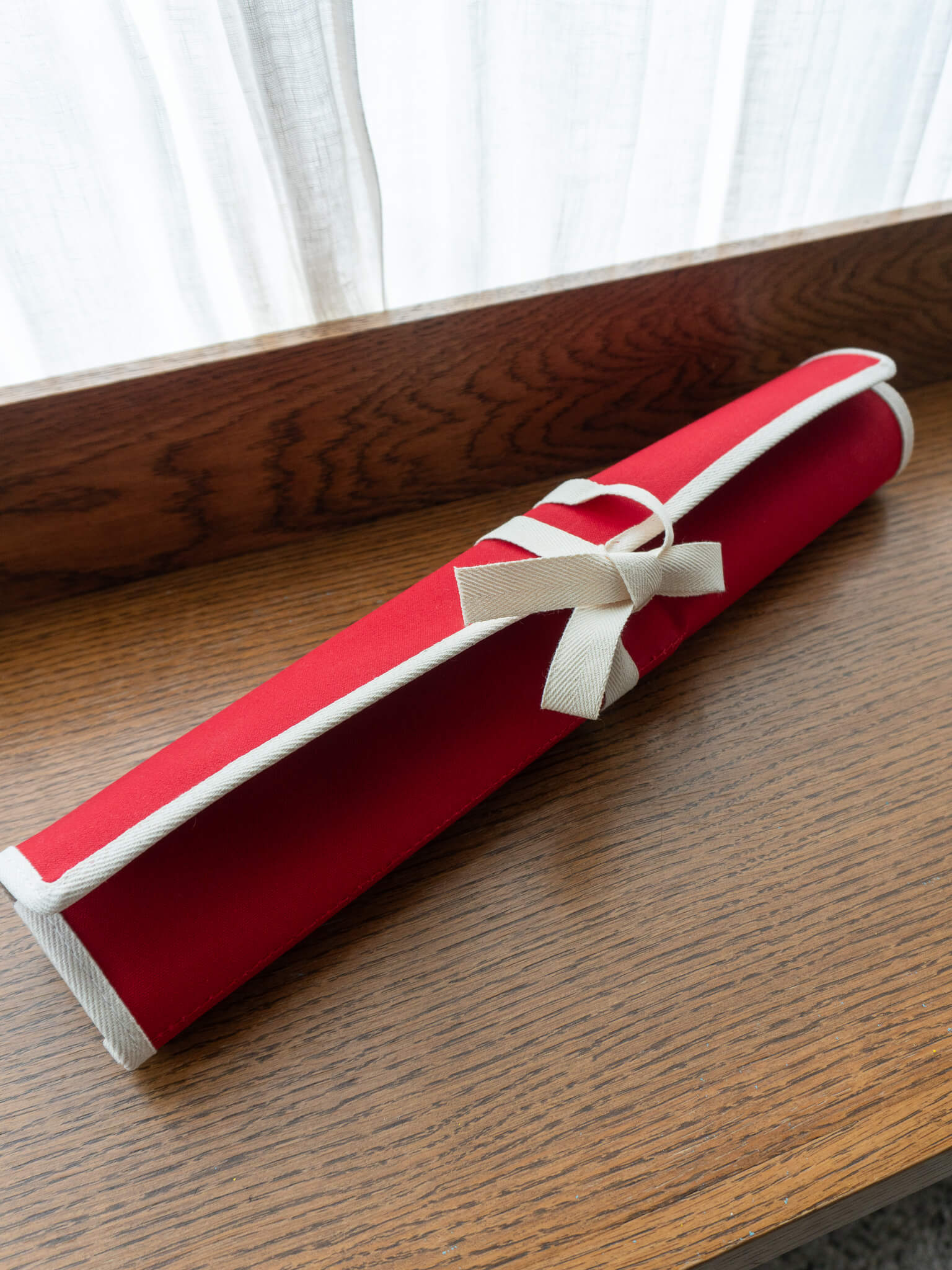 Red canvas knife roll designed for safe storage and transport of kitchen knives.