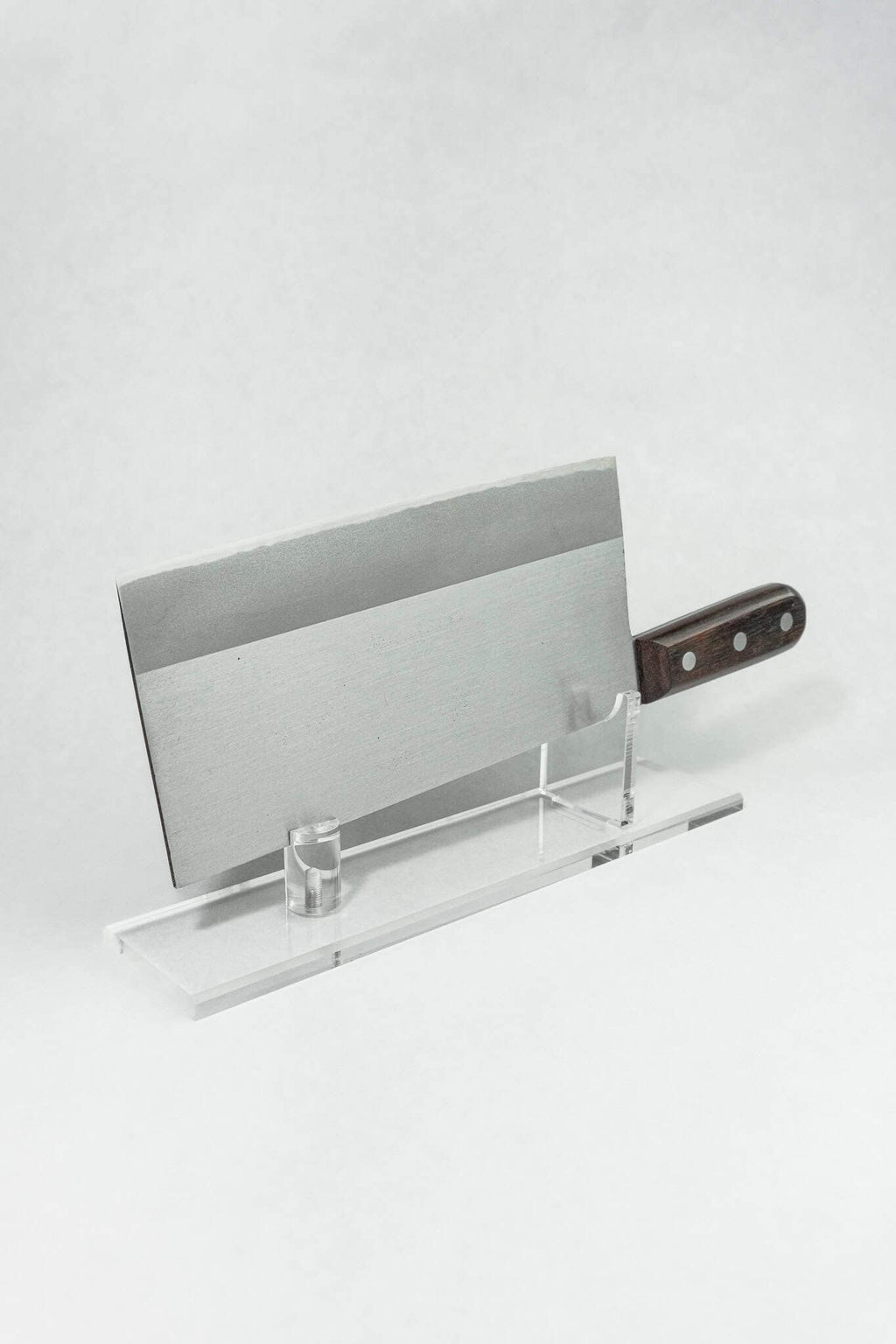 Premium fit and finish on a Japanese cleaver displayed on a clear stand against a white background. 