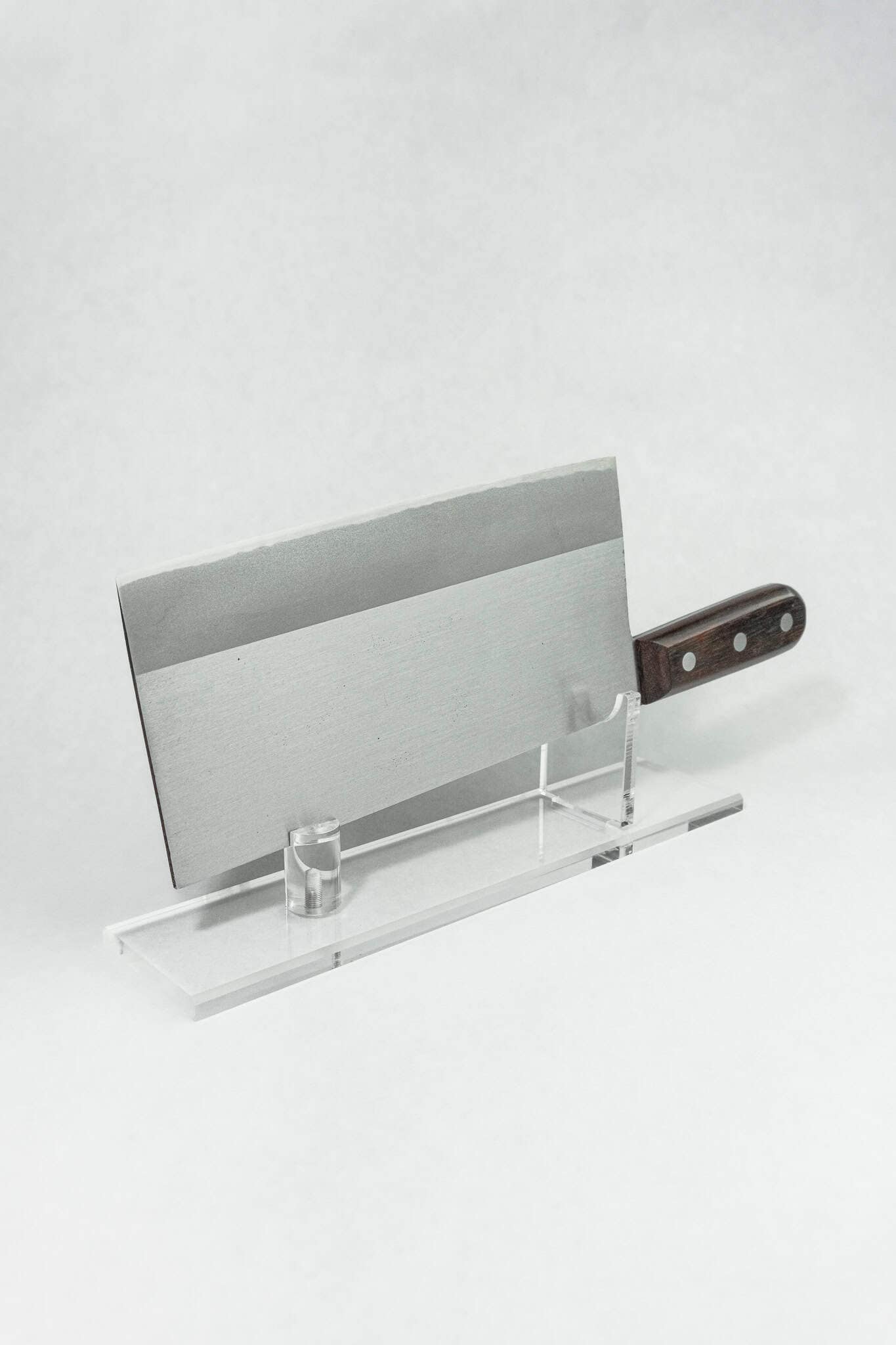 Premium fit and finish on a Japanese cleaver displayed on a clear stand against a white background. 