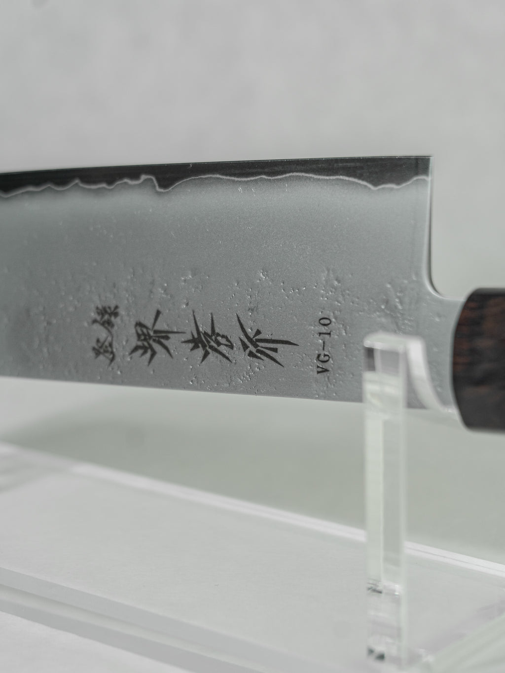 Close-up detail of the nakiri knife’s choil and blade, showcasing the smooth kasumi finish with wave-like patterning along the edge, highlighting the craftsmanship, balance, and layered steel construction.