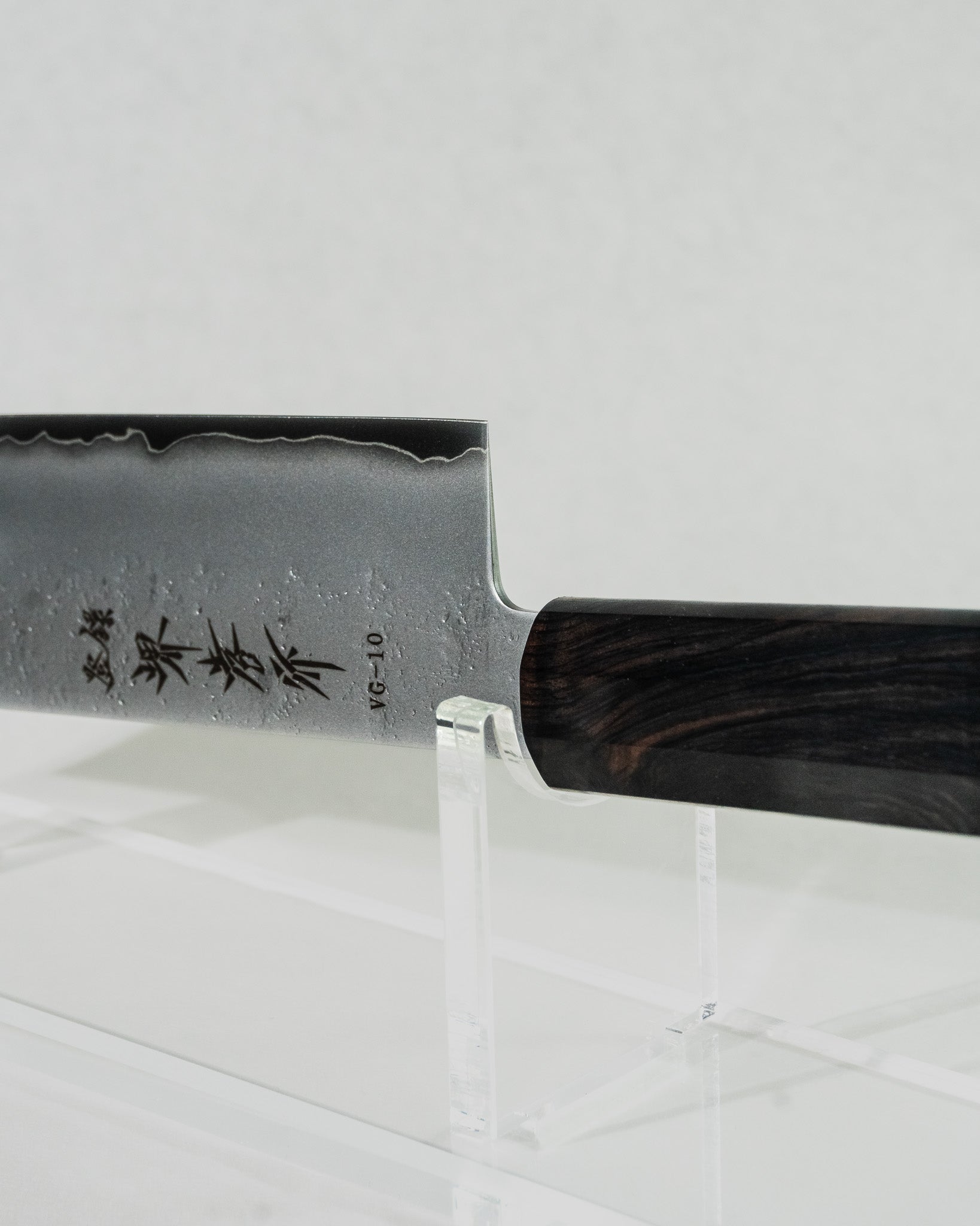 Close-up detail of the nakiri knife’s choil and blade, showcasing the smooth kasumi finish with wave-like patterning along the edge, highlighting the craftsmanship, balance, and layered steel construction.