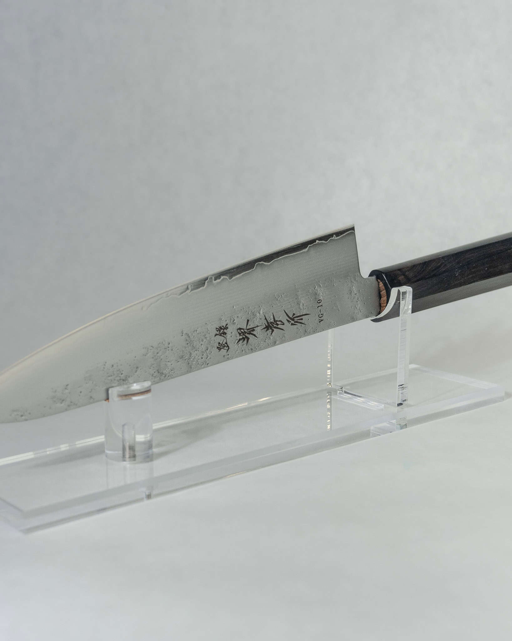 Close-up of Gyuto blade showing stainless nashiji cladding and polished VG-10 core with the Sakai Takayuki makers mark stamped on the side